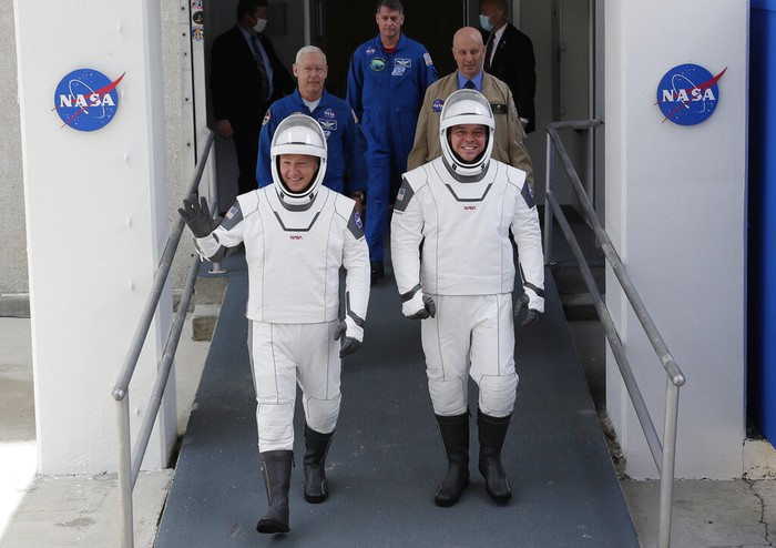 In this photo provided by NASA, astronauts Douglas Hurley, left, and Robert Behnken, wearing SpaceX spacesuits, prepare to leave the Neil A. Armstrong Operations and Checkout Building on their way to Pad 39-A, at the Kennedy Space Center in Cape Canaveral, Fla., Wednesday, May 27, 2020. The two astronauts will fly on a SpaceX test flight to the International Space Station. For the first time in nearly a decade, astronauts will blast into orbit aboard an American rocket from American soil, a first for a private company. (Bill Ingalls/NASA via AP)