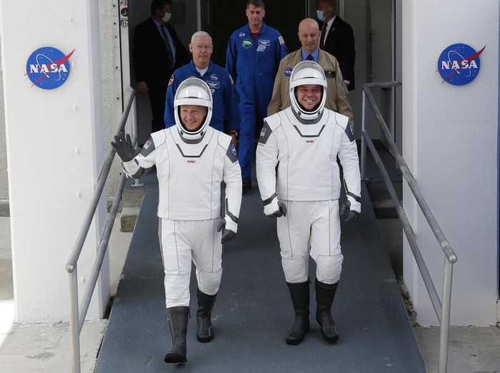 NASA astronauts Douglas Hurley, left, and Robert Behnken wave as they walk out of the Neil A. Armstrong Operations and Checkout Building on their way to Pad 39-A, at the Kennedy Space Center in Cape Canaveral, Fla., Wednesday, May 27, 2020. The two astronauts will fly on a SpaceX test flight to the International Space Station. For the first time in nearly a decade, astronauts will blast into orbit aboard an American rocket from American soil, a first for a private company. (AP Photo/John Raoux)