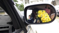 Pasangan pengantin tersebut mengenakan gaun pernikahan dan jas serta masker saat akan melangsungkan pernikahan di dalam mobil.