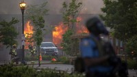 Petugas pemadam kebakaran berusaha memadamkan api dari gedung yang dibakar.