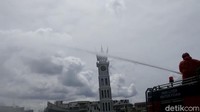 Petugas menyemprot taman dan kawasan pedestrian Jam Gadang. 