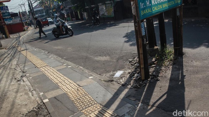 Warga menghindari tiang listrik, telepon maupun kabel serat optik yang berada di badan jalan di Jl WR Supratman, Ciputat Timur, Tangerang Selatan, Sabtu (30/5/2020). Tiang tersebut berada di badan jalan usai proyek pelebaran jalan, pertengahan 2018 lalu. Namun hingga kini belum ada proses pemindahan tiang sehingga membahayakan pengguna jalan. Selain itu, keberadaan tiang tersebut membuat pelebaran jalan belum efektif karena ada penyempitan ruang.