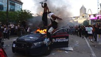 Warga yang marah menginjak-injak dan membakar mobil polisi. Ben Gray/Atlanta Journal-Constitution via AP.