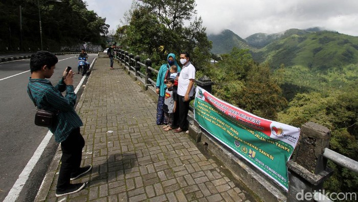 Warga berfoto dengan latar belakang pemandangan perbukitan di sekitar Gunung Lawu kawasan Cemoro Sewu, Jawa Timur, Jumat (29/5). Walaupun obyek wisata disekitar Gunung Lawu masih ditutup untuk memutus penyebaran virus Corona banyak warga mencari hiburan sekadar melepas penat dengan menikmati pemandangan alam.
