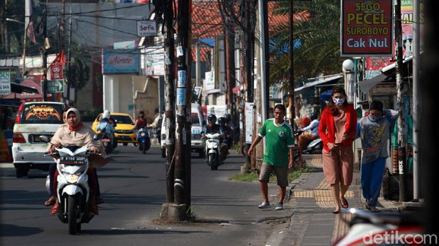Warga menghindari tiang listrik, telepon maupun kabel serat optik yang berada di badan jalan di Jl WR Supratman, Ciputat Timur, Tangerang Selatan, Sabtu (30/5/2020). Tiang tersebut berada di badan jalan usai proyek pelebaran jalan, pertengahan 2018 lalu. Namun hingga kini belum ada proses pemindahan tiang sehingga membahayakan pengguna jalan. Selain itu, keberadaan tiang tersebut membuat pelebaran jalan belum efektif karena ada penyempitan ruang.