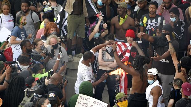 Demonstrators light an American flag on fire during a protest, Friday, May 29, 2020 in Atlanta. The protest started peacefully earlier in the day before demonstrators clashed with police. (AP Photo/Mike Stewart)