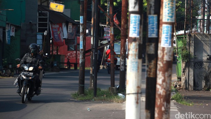 Warga menghindari tiang listrik, telepon maupun kabel serat optik yang berada di badan jalan di Jl WR Supratman, Ciputat Timur, Tangerang Selatan, Sabtu (30/5/2020). Tiang tersebut berada di badan jalan usai proyek pelebaran jalan, pertengahan 2018 lalu. Namun hingga kini belum ada proses pemindahan tiang sehingga membahayakan pengguna jalan. Selain itu, keberadaan tiang tersebut membuat pelebaran jalan belum efektif karena ada penyempitan ruang.