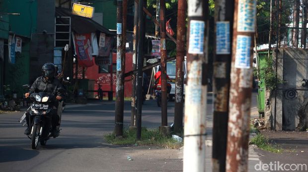 Warga menghindari tiang listrik, telepon maupun kabel serat optik yang berada di badan jalan di Jl WR Supratman, Ciputat Timur, Tangerang Selatan, Sabtu (30/5/2020). Tiang tersebut berada di badan jalan usai proyek pelebaran jalan, pertengahan 2018 lalu. Namun hingga kini belum ada proses pemindahan tiang sehingga membahayakan pengguna jalan. Selain itu, keberadaan tiang tersebut membuat pelebaran jalan belum efektif karena ada penyempitan ruang.