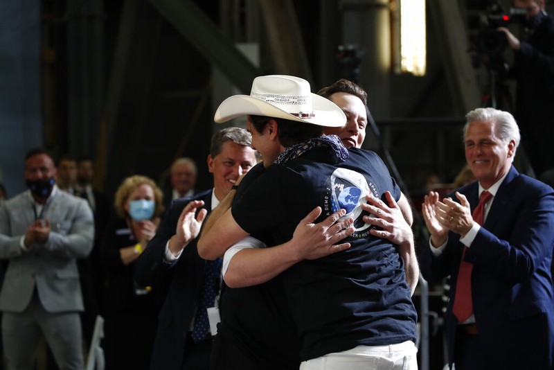 Tesla and SpaceX Chief Executive Officer Elon Musk hugs his brother Kimbal Musk during an event at the Vehicle Assembly Building on Saturday, May 23, 2020, at NASA's Kennedy Space Center in Cape Canaveral, Fla. The event occurred after a rocket ship designed and built by SpaceX lifted off on Saturday with two Americans on a history-making flight to the International Space Station. House Minority Leader Kevin McCarthy of Calif., applauds at right. (AP Photo/Alex Brandon)