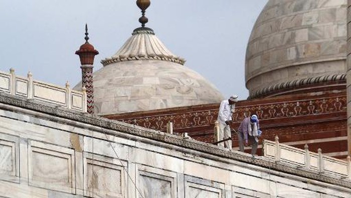 In this picture taken on May 30, 2020, workers stand on the railing of the Taj Mahal after it was damaged due to heavy rainstorm in Agra. (Photo by Pawan Sharma / AFP)