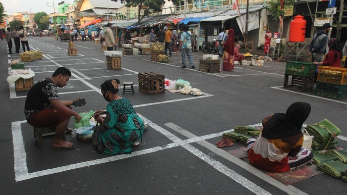 JAGA JARAK DI PASAR TRADISIONAL Petugas membantu pedagang memindahkan dagangannya di depan Pasar Pegirian, Surabaya, Jawa Timur, Minggu (31/5/2020). Perusahaan Daerah (PD) Pasar Surya Kota Surabaya menerapkan jaga jarak (physical distancing) di pasar itu dengan membuat garis petak-petak bagi pedagang dan mulai ditempati hari ini Minggu (31/5) sebagai langkah pencegahan penyebaran COVID-19. ANTARA FOTO/Didik Suhartono/foc.
