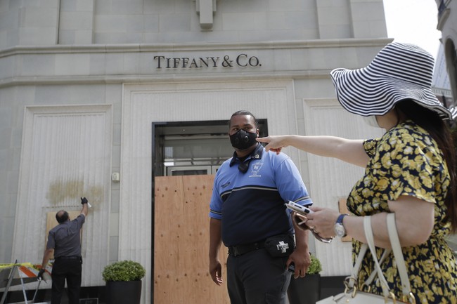 Tak cuma butik pakaian, butik perhiasan juga terdampak. Di foto ini, petugas terlihat membersihkan coretan di dinding depan butik perhiasan Tifanny & Co. (Foto: AP/Marcio Jose Sanchez)