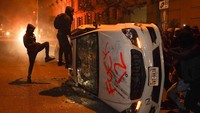 Demonstran juga merusak mobil yang terparkir di bahu jalan. Mobil dijungkirkan dan kaca dipecahkan. AP Photo/Evan Vucci.