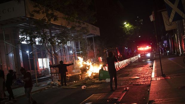 Protesters run down a street where a fire was started outside a Gucci store during a rally for George Floyd, Sunday, May 31, 2020, in New York. Protests were held throughout the city over the death of Floyd, a black man in police custody in Minneapolis who died after being restrained by police officers on Memorial Day. (AP Photo/Wong Maye-E)
