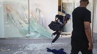 Penjarah memasuki pertokoan melewati kaca yang telah dipecahkan. Kemudian mereka menjarah barang-barang di dalam toko dan beranjak pergi. AP Photo/Marcio Jose Sanchez.