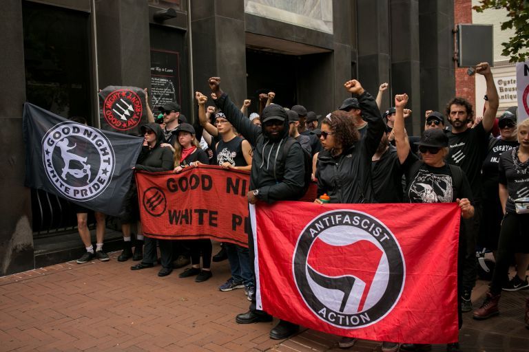 Members of ANTIFA get in formation after entering the security checkpoint required to enter the mall in downtown Charlottesville, Virginia, one-year after the violent white nationalist rally that left one person dead and dozens injured. (Photo by Logan Cyrus / AFP)        (Photo credit should read LOGAN CYRUS/AFP via Getty Images)
