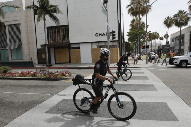 Polisi tampak melintas di depan butik Chanel yang berlokasi di salah satu tikungan Rodeo Drive. Butik rumah mode asal Prancis itu pun tak luput dari aksi vandalisme. (Foto: AP/Marcio Jose Sanchez)