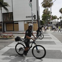 Polisi tampak melintas di depan butik Chanel yang berlokasi di salah satu tikungan Rodeo Drive. Butik rumah mode asal Prancis itu pun tak luput dari aksi vandalisme. (Foto: AP/Marcio Jose Sanchez)