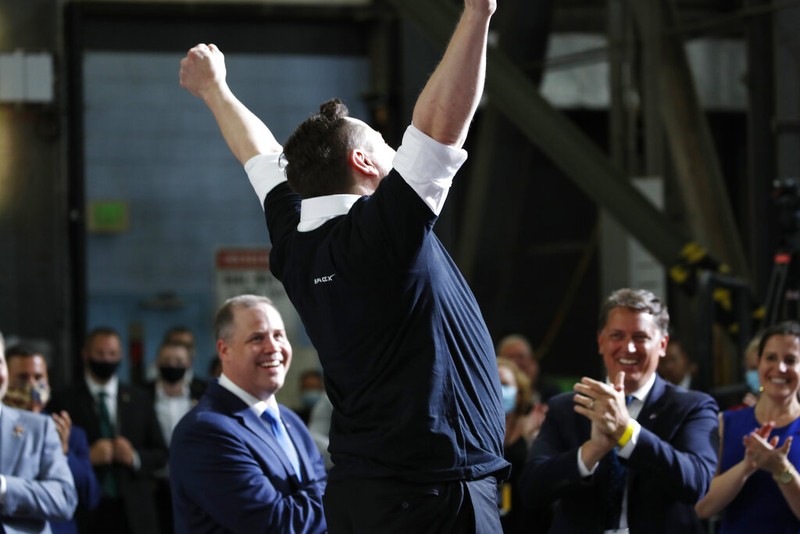 Tesla and SpaceX Chief Executive Officer Elon Musk jumps in the air as people applaud during an event at the Vehicle Assembly Building on Saturday, May 23, 2020, at NASA's Kennedy Space Center in Cape Canaveral, Fla. The event occurred after a rocket ship designed and built by SpaceX lifted off on Saturday with two Americans on a history-making flight to the International Space Station. NASA Administrator Jim Bridenstine looks on at left. (AP Photo/Alex Brandon)