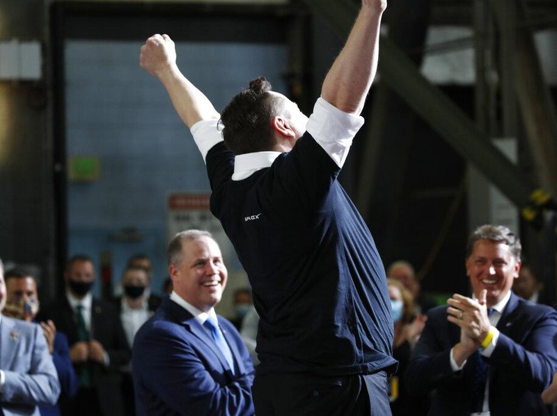 Tesla and SpaceX Chief Executive Officer Elon Musk jumps in the air as people applaud during an event at the Vehicle Assembly Building on Saturday, May 23, 2020, at NASA's Kennedy Space Center in Cape Canaveral, Fla. The event occurred after a rocket ship designed and built by SpaceX lifted off on Saturday with two Americans on a history-making flight to the International Space Station. NASA Administrator Jim Bridenstine looks on at left. (AP Photo/Alex Brandon)