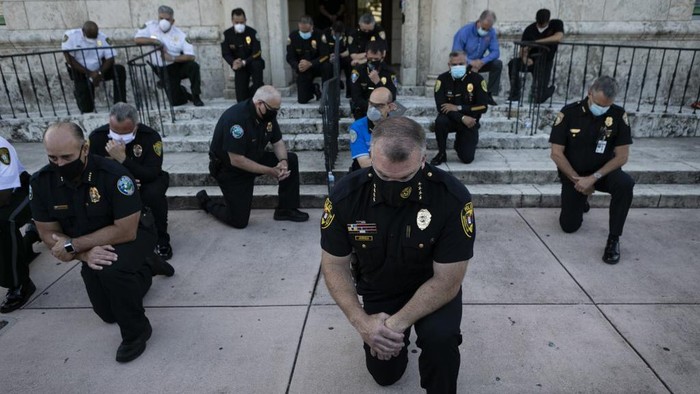 Police officers kneel during a rally in Coral Gables, Florida on May 30, 2020 in response to the recent death of George Floyd, an unarmed black man who died while being arrested and pinned to the ground by a Minneapolis police officer. - Clashes broke out and major cities imposed curfews as America began another night of unrest Saturday with angry demonstrators ignoring warnings from President Donald Trump that his government would stop violent protests over police brutality 