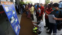 Di luar gedung masyarakat tampak berkumpul karena belum mendaftarkan diri secara online sehingga tidak diizinkan masuk.