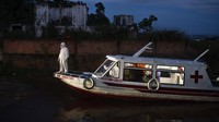 Seorang petugas medis berdiri di atas perahu yang dialifungsikan menjadi ambulans untuk mengangkut para pasien COVID-19 yang berada di kawasan Amazon, Brasil.