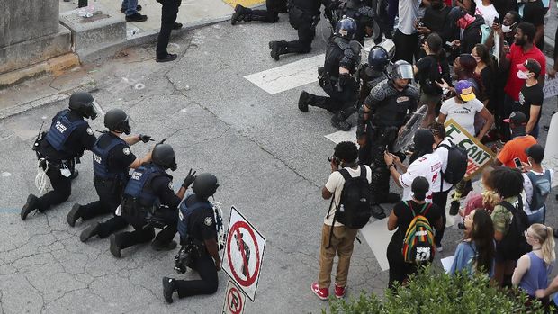 In a show of peace and solidarity, law enforcement officials with riot shields kneel in front of protesters Monday, June 1, 2020, during a fourth day of protests over the death of George Floyd in Minneapolis. (Curtis Compton/Atlanta Journal-Constitution via AP)