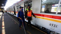 Petugas membantu seorang tuna netra naik ke commuter line.