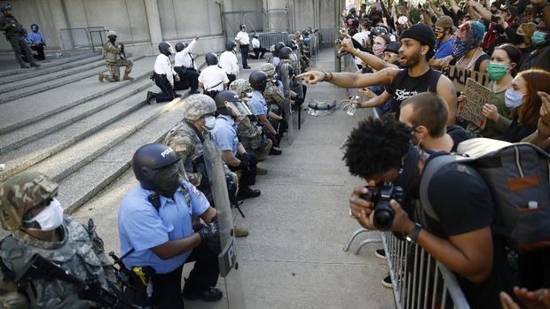 Philadelphia police and National Guard take a knee at the suggestion of Philadelphia Police Deputy Commissioner Melvin Singleton, unseen, outside Philadelphia Police headquarters in Philadelphia, Monday, June 1, 2020 during a march calling for justice over the death of George Floyd, Floyd died after being restrained by Minneapolis police officers on May 25. (AP Photo/Matt Rourke)