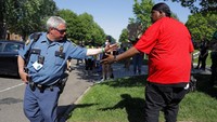 Polisi dan demonstran saling sapa di tengah aksi memprotes kematian George Floyd di St Paul pada 1 Juni 2020.