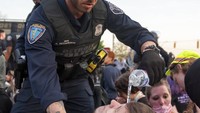 Seorang polisi membantu membasuh mata demonstran yang terkena gas air mata di Detroit pada 2 Juni 2020. David Guralnick/Detroit News via AP.