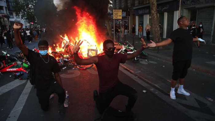 A protester kicks into a tear gas canister during a demonstration Tuesday, June 2, 2020. Paris riot officers fired tear gas as scattered protesters threw projectiles and set fires at an unauthorized demonstration against police violence and racial injustice. Several thousand people rallied peacefully for two hours around the main Paris courthouse in homage to George Floyd and to Adama Traore, a French black man who died in police custody. (AP Photo/Rafael Yaghobzadeh)