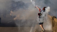 Bukannya mundur, seorang pengunjukrasa ini justru melempar kembali gas air mata ke arah polisi. Mike Morones/The Free Lance-Star via AP.