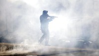 Seorang polisi bergerak melewati kepulan gas air mata untuk membubarkan kerumunan pengunjukrasa di Philadelphia. AP Photo/Matt Rourke.