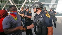 Demonstran dan polisi saling berjabat tangan di Salt Lake City pada 1 Juni 2020. AP Photo/Rick Bowmer.