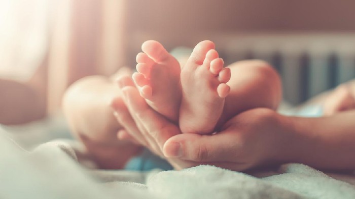hamil dan melahirkan saat pandemi corona Feet of new born Baby in Hands of parents