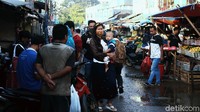 Seorang warga menggendong anaknya melintas di antara lalu lalang warga yang berbelanja di pasar tradisional tersebut.