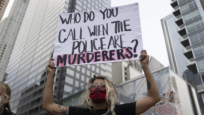 A woman holds up a sign during a demonstration in Los Angeles, Friday, May 29, 2020, in protest over the death of George Floyd, who died in police custody on Memorial Day in Minneapolis. (AP Photo/Christian Monterrosa)