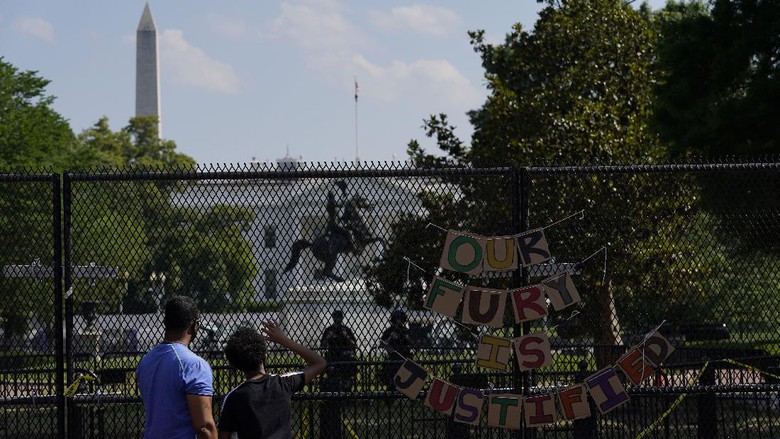 With the White House in the background, people stand against a fence Thursday, June 4, 2020, in Washington as demonstrators protest over the death of George Floyd, a black man who was in police custody in Minneapolis. Floyd died after being restrained by Minneapolis police officers. (AP Photo/Evan Vucci)