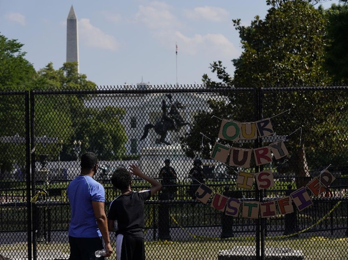 With the White House in the background, people stand against a fence Thursday, June 4, 2020, in Washington as demonstrators protest over the death of George Floyd, a black man who was in police custody in Minneapolis. Floyd died after being restrained by Minneapolis police officers. (AP Photo/Evan Vucci)