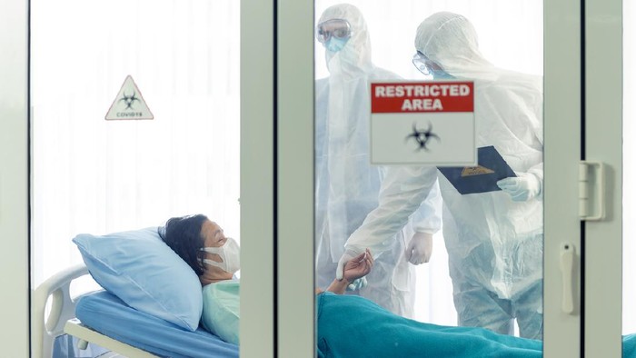 Doctor examines corona or covid-19 virus patient in the clean room with covid 19 and restricted area sign in front of the room