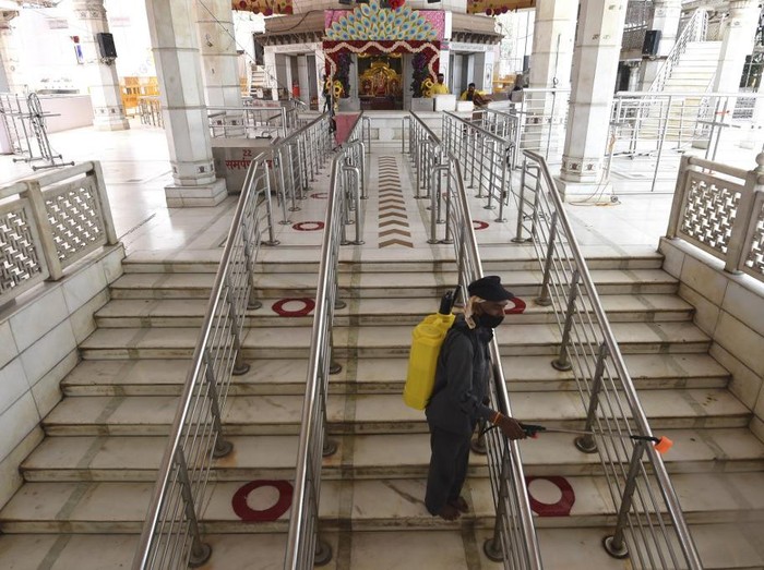A worker sprays disinfectant inside a temple after the government eased a nationwide lockdown imposed as a preventive measure against the COVID-19 coronavirus in New Delhi on June 6, 2020. (Photo by Money SHARMA / AFP)