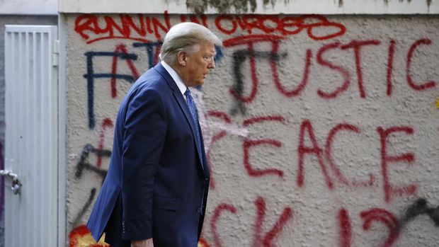 President Donald Trump walks from the White House past graffiti in Lafayette Park to visit St. John's Church in Washington on Monday, June 1, 2020. (AP Photo/Patrick Semansky)