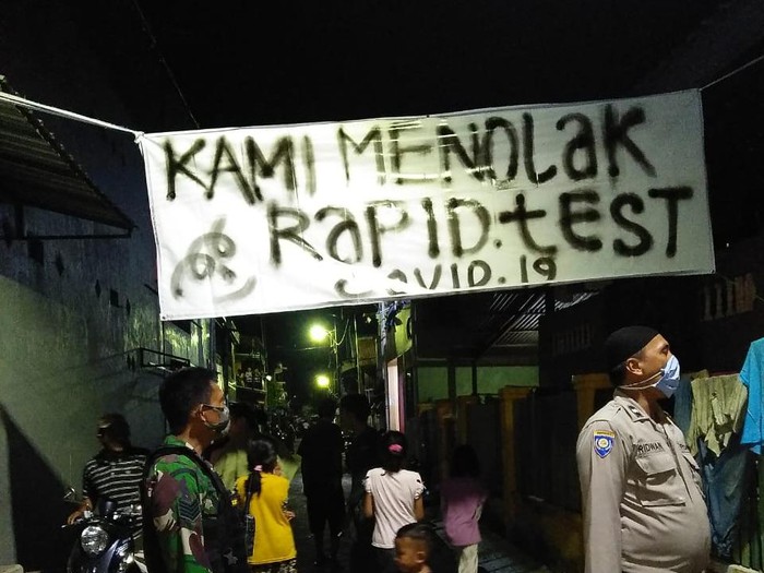Aparat mencopot spanduk warga menolak rapid test (dok. Istimewa).