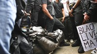 Sejumlah demonstran berdiri di sekitar patung Edward Colston yang dirobohkan saat menggelar aksi Black Lives Matter di kawasan Bristol, Inggris, pada akhir pekan kemarin. Edward Colston diketahui merupakan seorang pedagang budak di masa silam.