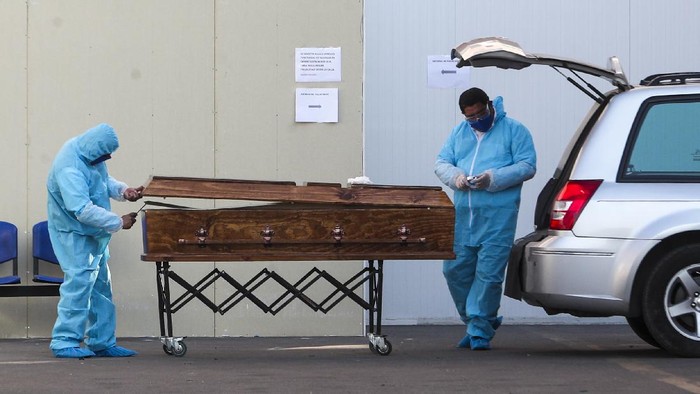 Petugas pemakaman di Chile memakai alat pelindung diri sebelum membawa jenazah pasien Corona Funeral workers wearing protective gear as a precaution against the spread of the new coronavirus, prepare to receive the remains of a person who has died from the new coronavirus, at the San Jose hospital in Santiago, Chile, Tuesday, May 26, 2020. (AP Photo/Esteban Felix)