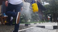 Petugas harus menjalani rangakaian pemeriksaan saat akan bekerja. Salah satu disemprot disinfektan sebelum memasuki kantor.