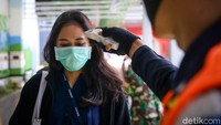 Petugas melakukan pengecekan suhu tubuh bagi para calon penumpang yang hendak memasuki Stasiun Sudirman.