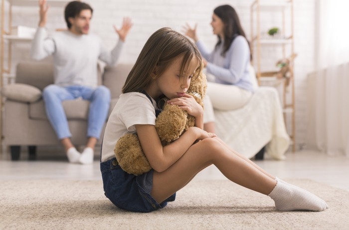 Ilustrasi Anak Korban Perceraian Family Problems. Cute Little Girl Suffering From Parents Arguing, Sitting On Floor With Teddy Bear, Feeling Abandonned And Lonely